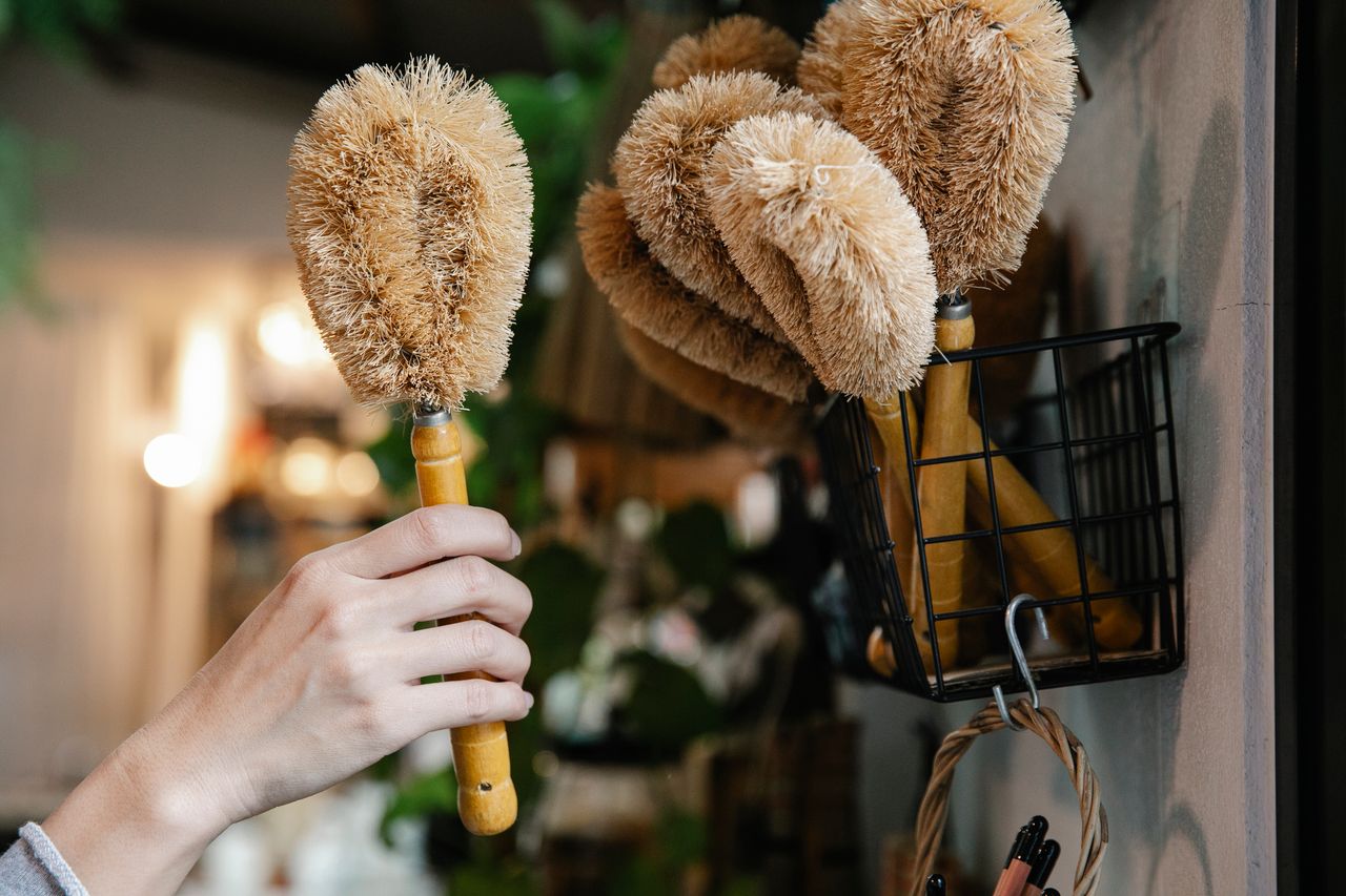 stats-img Close-up of a hand selecting eco-friendly cleaning brushes from a basket indoors.