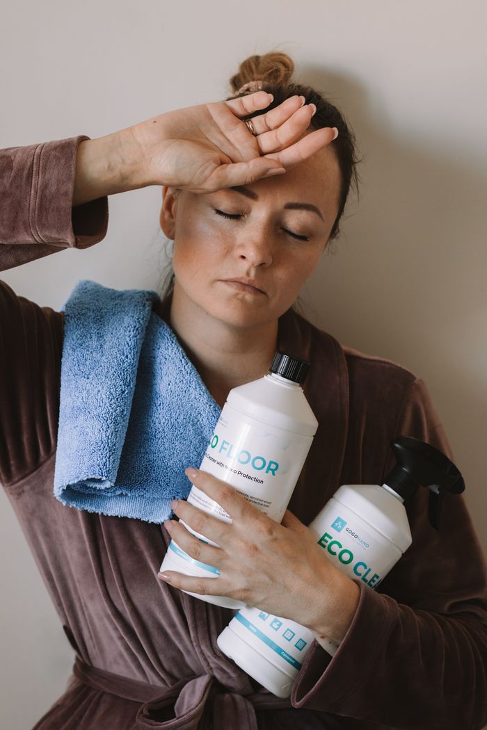 portfolio-02 Woman holding eco-friendly cleaning products with blue microfiber cloth indoors.