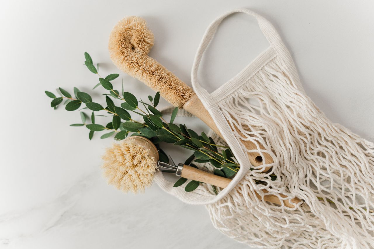 creative-approach-img Eco-friendly cleaning brushes and eucalyptus branch in a net bag on a marble surface.